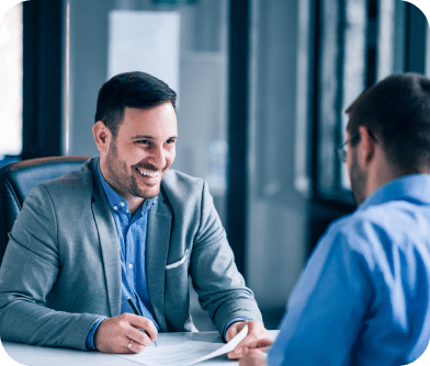 Two men sitting at a table talking to each other.