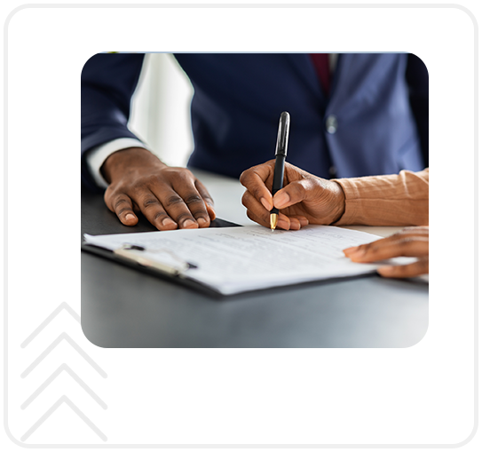 A person signing papers with another person holding a pen.